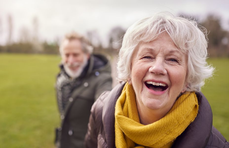 photo of carer walking outdoors with her husband, they are both looking at the camera happy